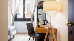 Ein Hotelzimmer mit einem Bett, einem Schreibtisch mit Lampe, einem Sessel und einem fenster mit Vorhängen.