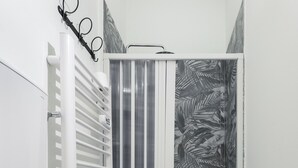 Ein Badezimmer mit Toilette, Bidet und Duschkabine mit gestreifter Duschvorhang.