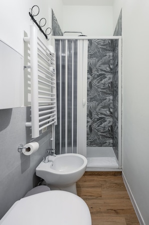 Ein Badezimmer mit Toilette, Bidet und Duschkabine mit gestreifter Duschvorhang.