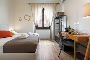 Hotelkamer met een bed, bureau, stoel, raam met gordijnen en uitzicht op het balkon.