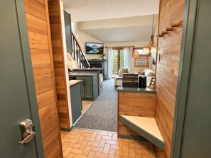 A modern kitchen with a central island, a dining area with a table and chairs, and a living space with a sofa and a fireplace.
