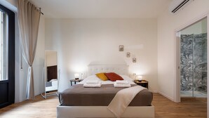 A bedroom with a large bed, bedside tables, a mirror, and a view of a tropical wallpapered area. - MusArt Yellow Room (Firenze)