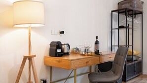 Une pièce de taille modeste, comprenant un bureau en bois, une chaise, une lampe, une machine à café et un meuble de rangement avec des étagères.