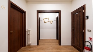 Un couloir doté d’un plancher en bois, de portes numérotées et d’un extincteur.