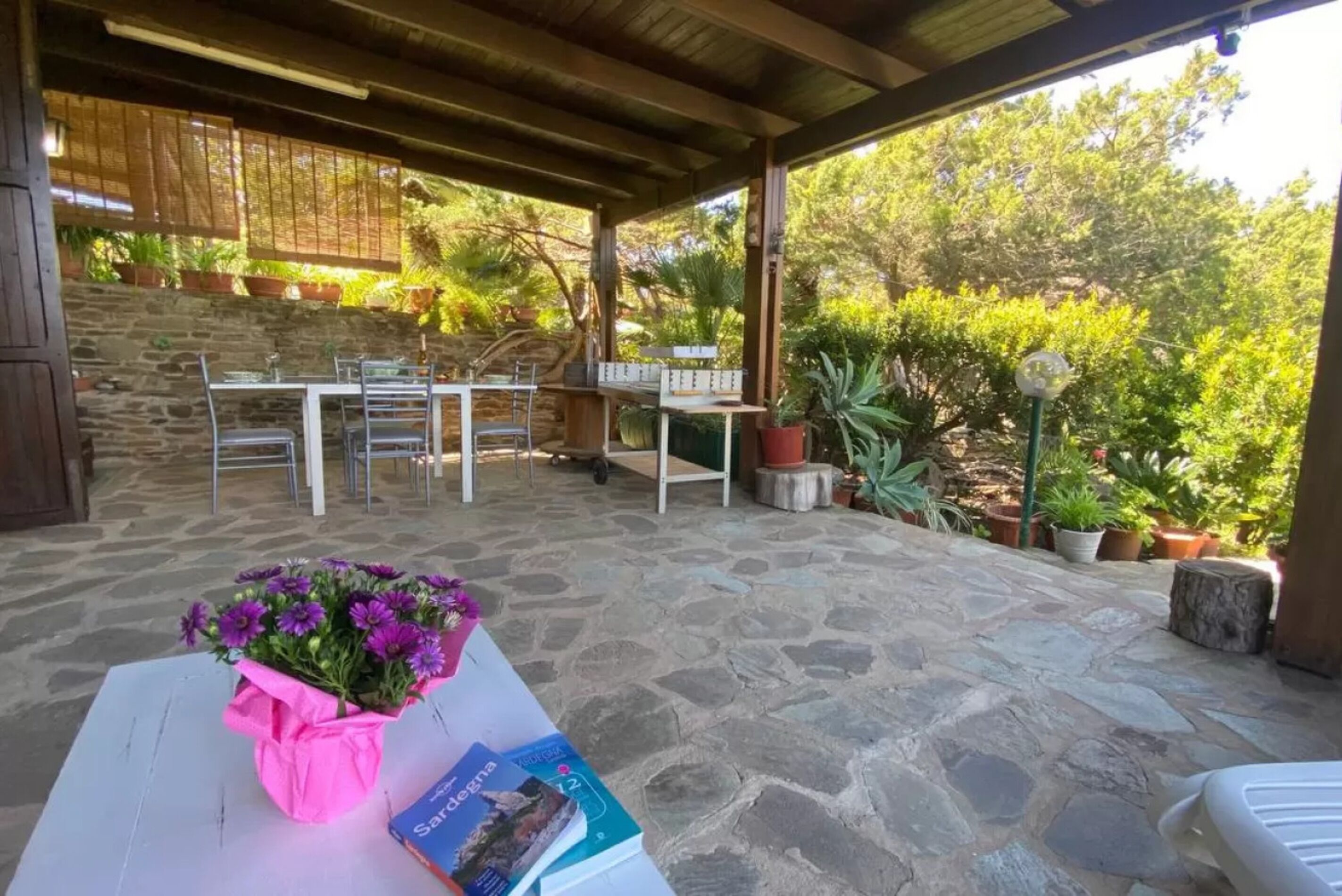 Une terrasse extérieure avec un sol en pierre, des tables, des chaises et des plantes en pot.