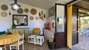 A dining area with a table set for two, a chair, a small table, and a cabinet with a mirror. - Relaxing Home Near the Best Beaches of Stintino (Stintino)