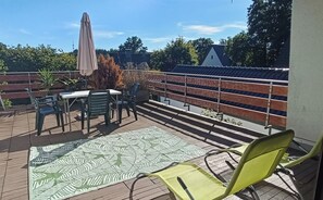 An outdoor patio with a table and chairs, a patterned rug, and a metal railing. - Cozy vacation apartment with a large rooftop terrace in an upscale residential neighborhood.   (Halver)