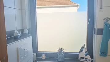 A bathroom with a toilet, a window, and a view of a building outside.