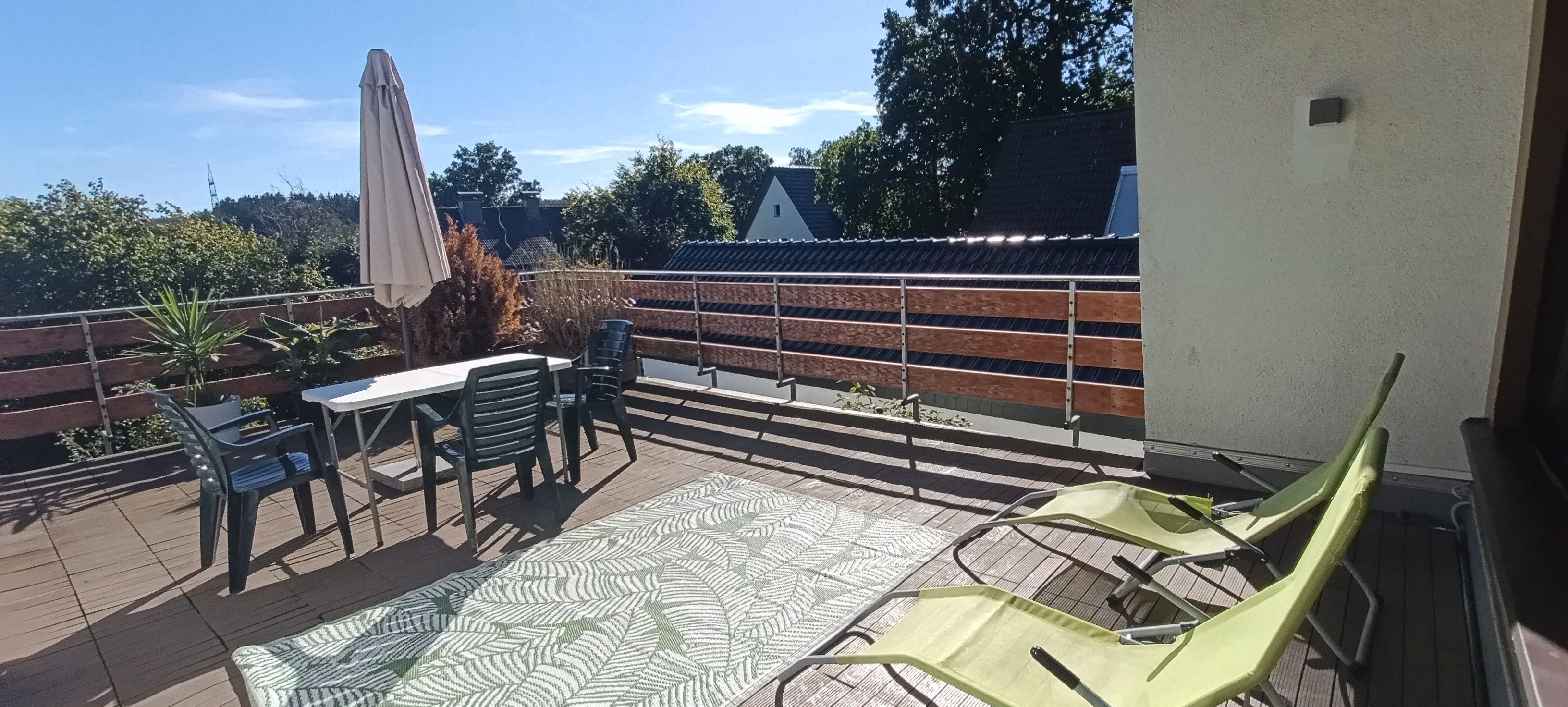 Ein möblierter Außenbereich mit Terrasse, Tisch, Stühlen, einem gemusterten Teppich und Blick auf die Umgebung.