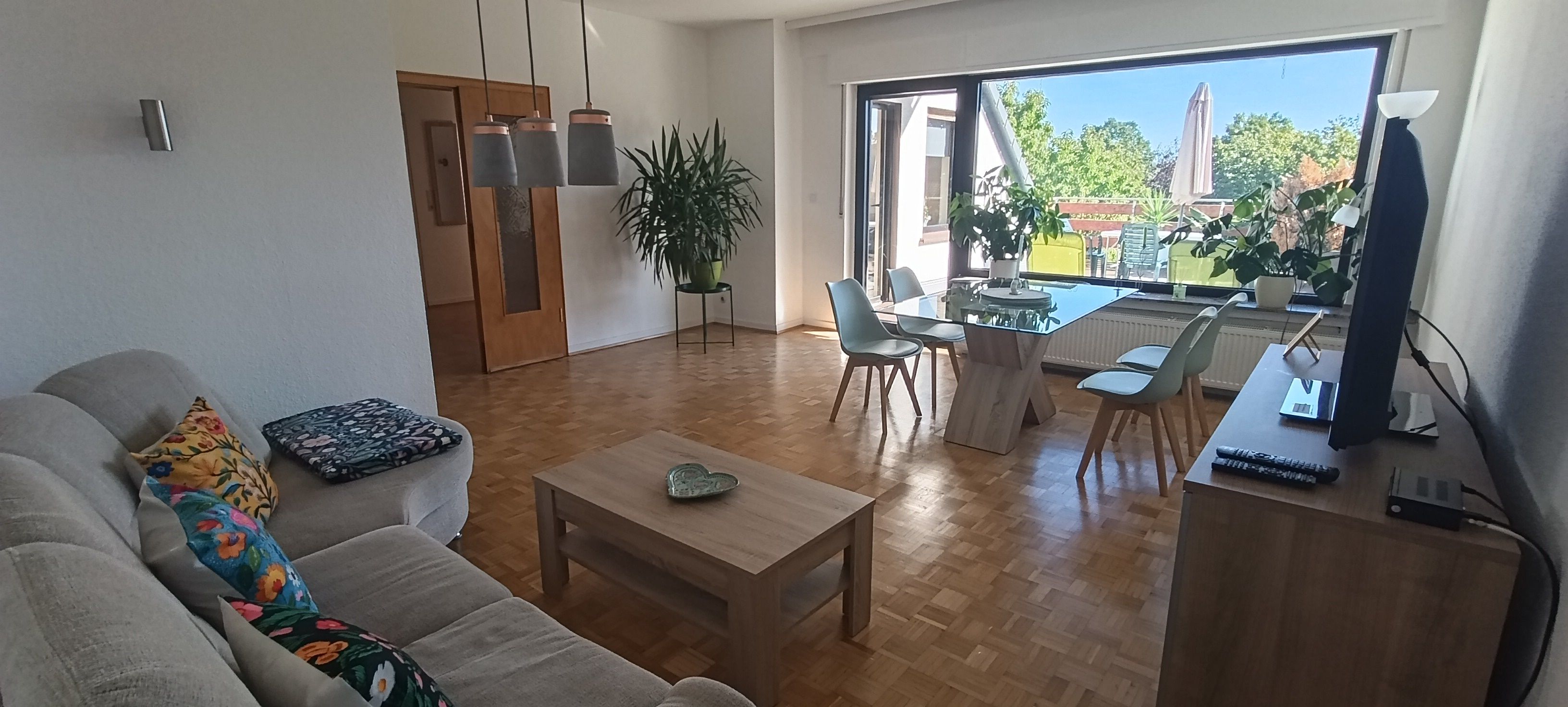 A living room with a sofa, coffee table, and dining area with chairs and a table.
