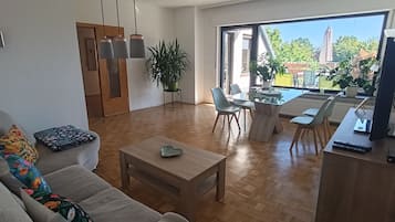 A living room with a sofa, coffee table, and dining area with chairs and a table.