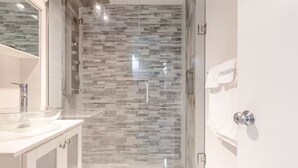 A modern bathroom with a glass-enclosed shower, a white sink, and a tiled backsplash.