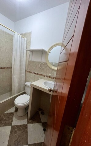 Bathroom features a white toilet, sink, and shower area with a checkered tile floor.