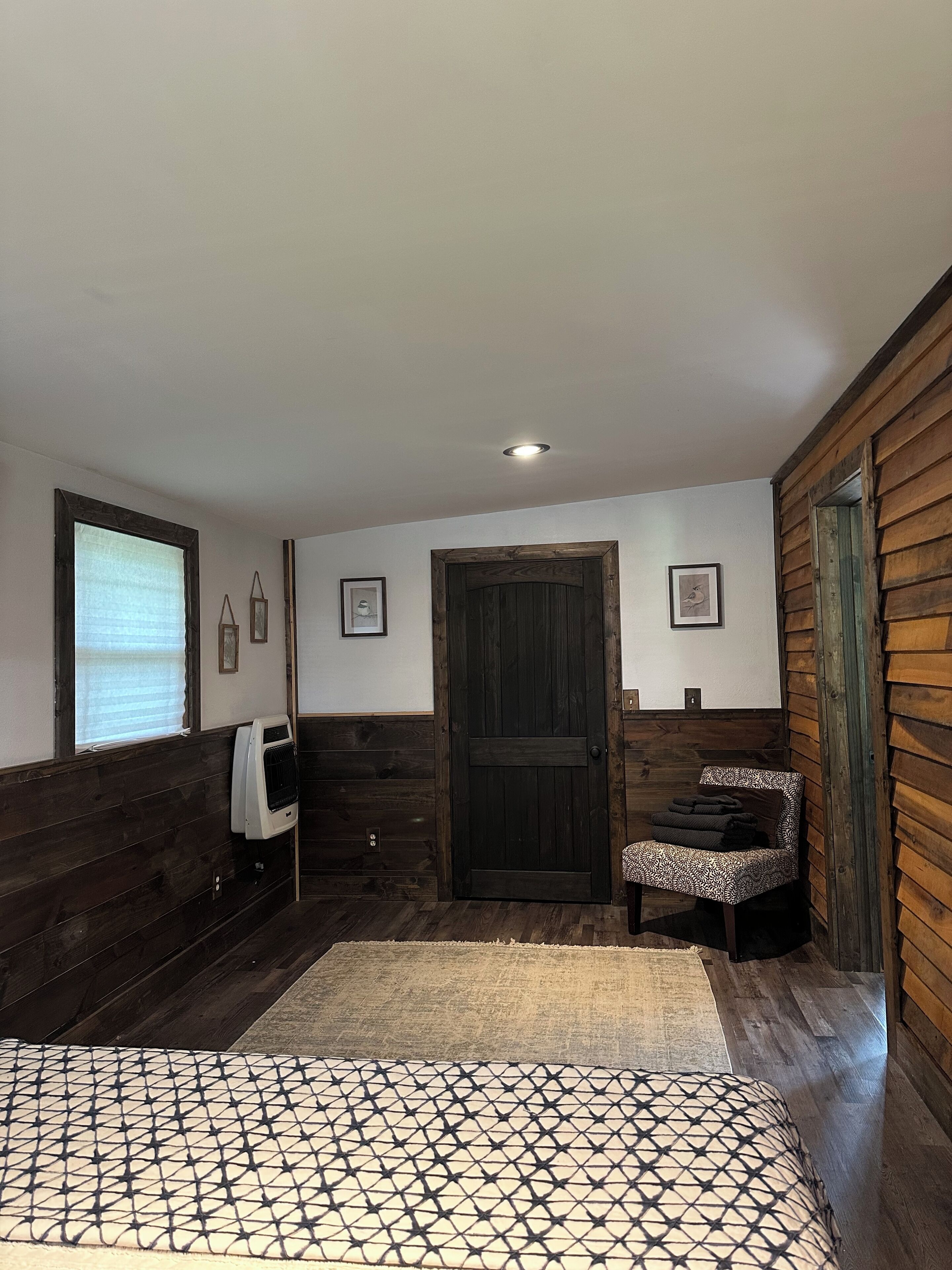 Une pièce avec des lambris en bois, une grande porte, un banc et un tapis à motifs.