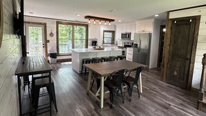 A spacious kitchen with a central island, wooden flooring, and a dining area with a bench.
