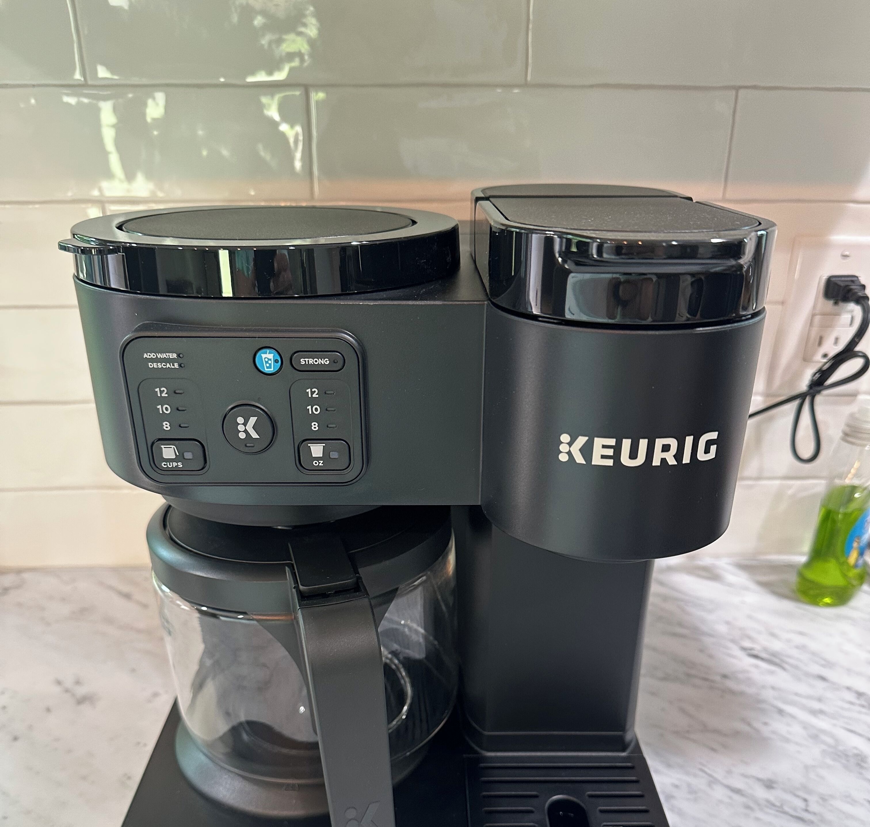 Een Keurig koffiezetapparaat met een digitaal display, een glazen kan en een waterreservoir.