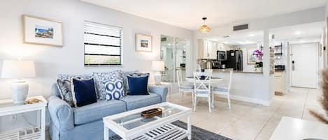 A modern living room with a sofa, coffee table, and dining area.
