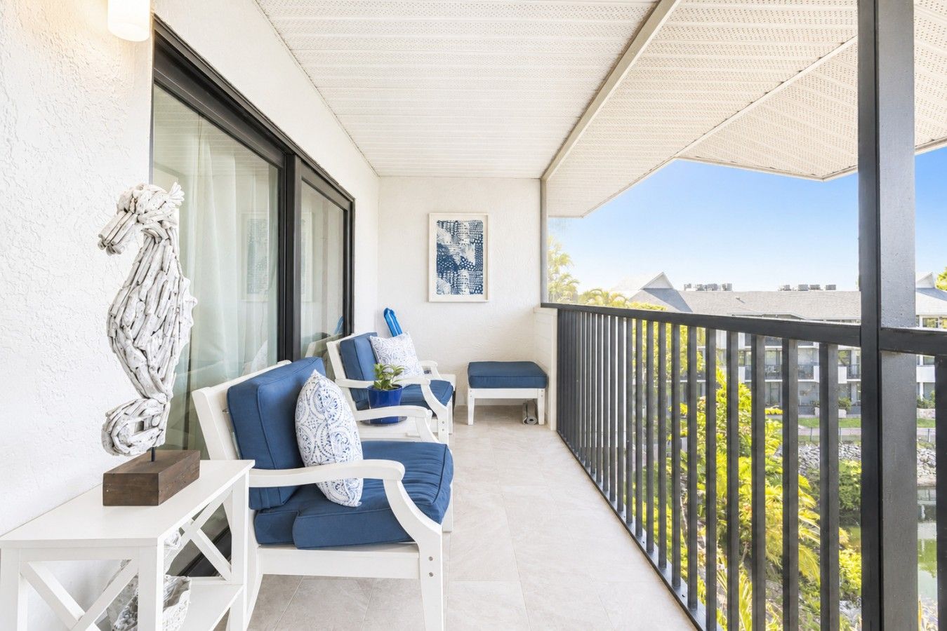 Un balcon avec un plafond blanc, un canapé bleu, une petite table et une plante en pot.