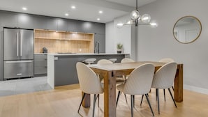 A modern kitchen with grey cabinets, a wooden island, and a dining area with a wooden table and chairs.