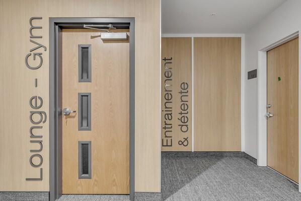 En hotelindgang med en trædør, der er mærket "Lounge - Gym" og et skilt, der angiver "Træning og afslapning".