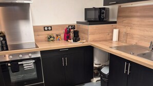 A modern kitchen with black cabinets, stainless steel appliances, and a wooden countertop. - L'Atelier T2 Cosy on the first floor (Saint-Gaudens)