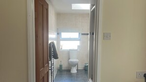 Une salle de bain avec des toilettes, une fenêtre et un sol carrelé.