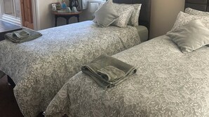 Une chambre d’hôtel avec deux lits, une petite table avec une lampe et une fenêtre avec des rideaux.