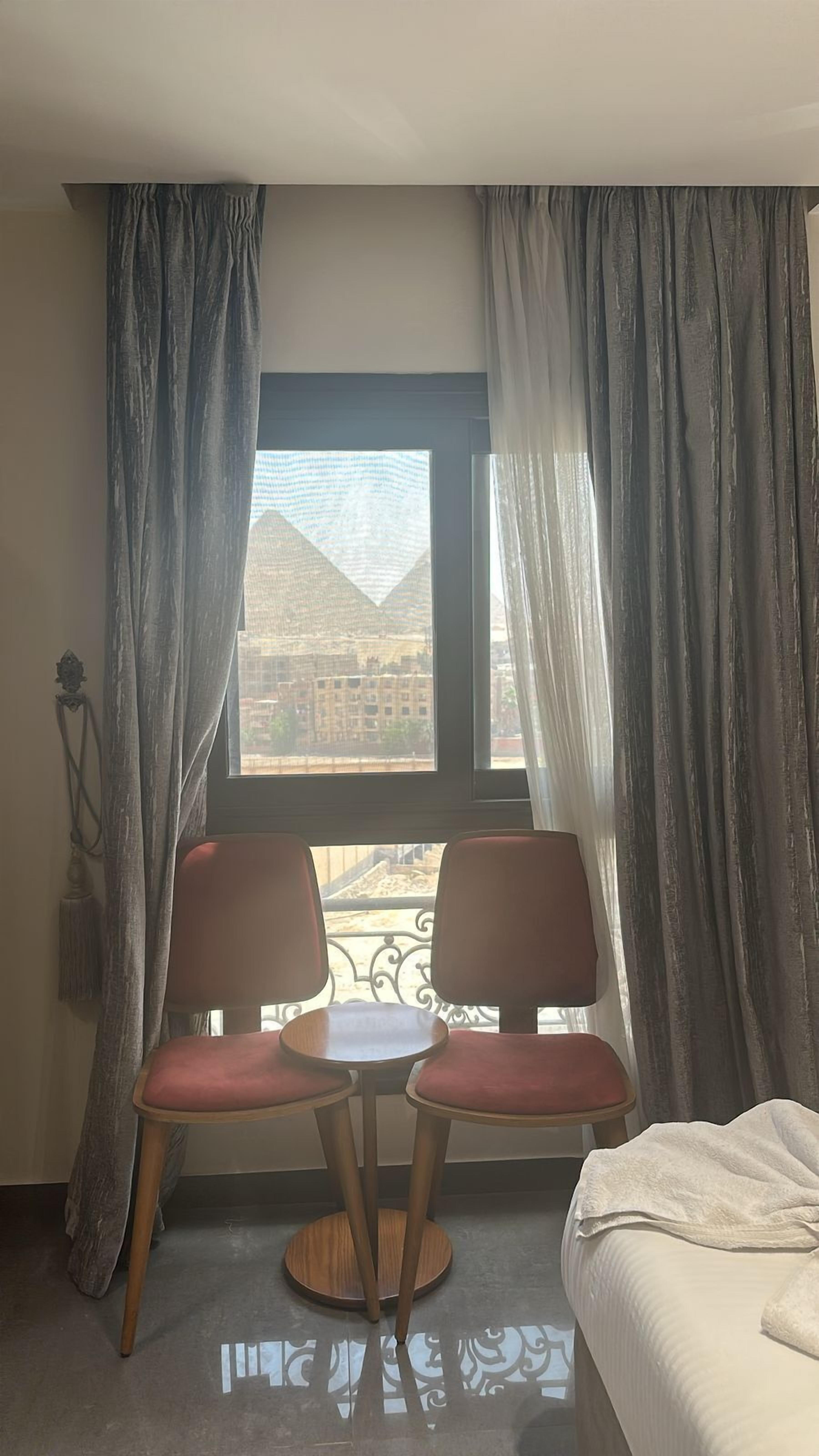 A hotel room with two chairs, a small table, and a bed.