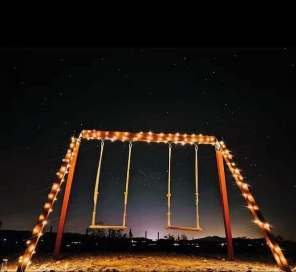 A swing set with lights against a night sky.