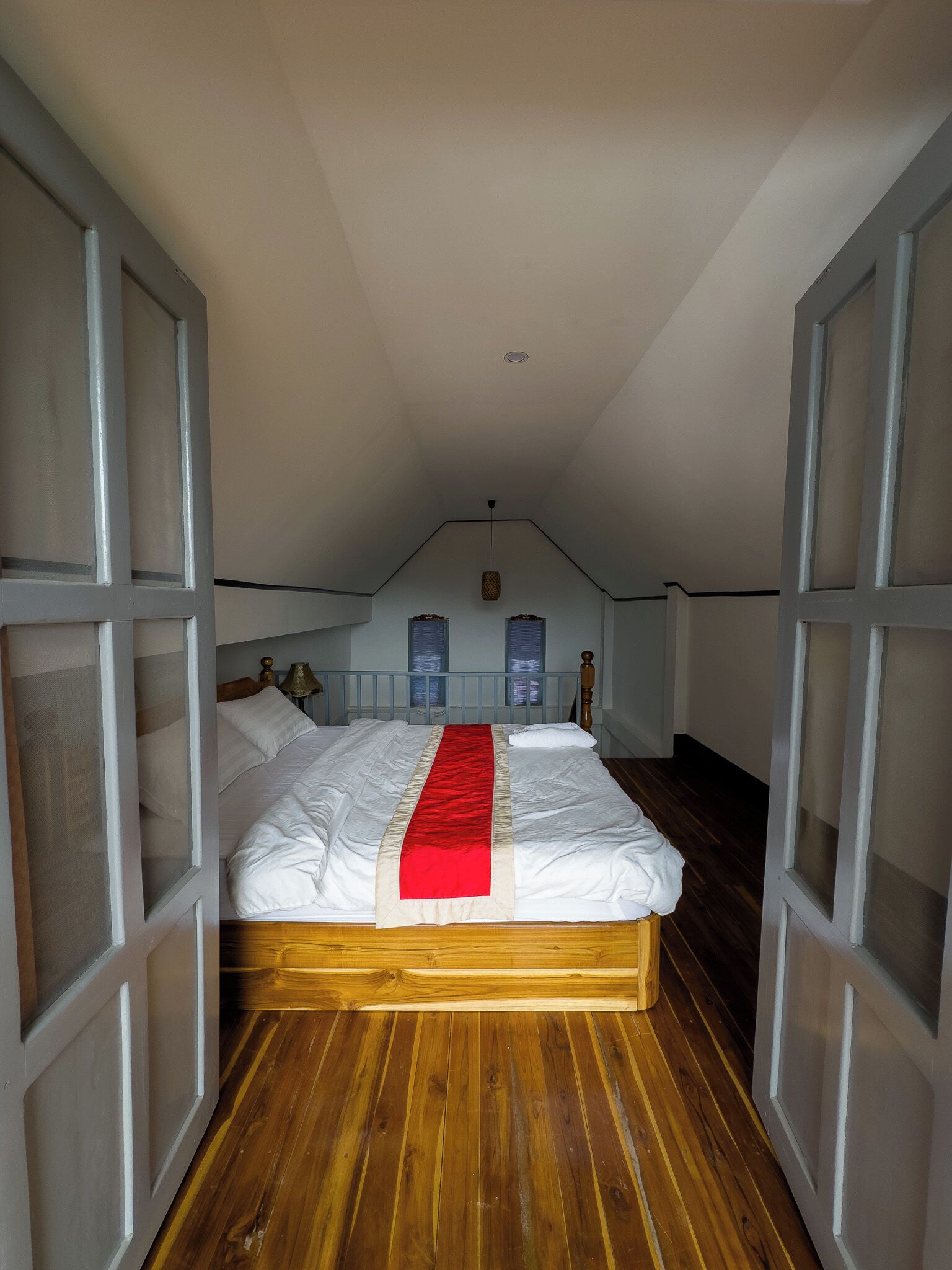 A bedroom with a wooden bed, white bedding, and a red runner.