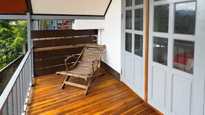 A wooden deck with a bench, a hanging light fixture, and a large window with multiple panes. - BANSUAN Homes (Luang Prabang)