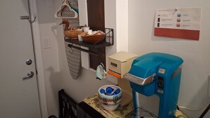 Uma cozinha com cafeteira, cesta de pão e um aviso com instruções fixado na parede.