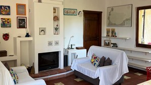 Un salon chaleureux avec une cheminée, deux canapés, une petite table et divers éléments de décoration murale.