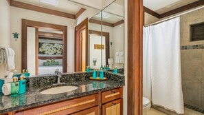 Ein Badezimmer mit großem Spiegel, Waschbecken und Duschbereich.