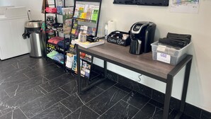 Un bancone di un bar con una macchina per caffè, un cestino e una selezione di articoli a tema caffè.