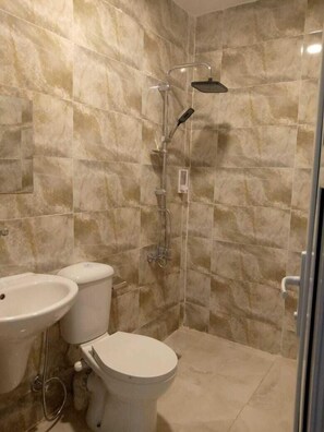 Een aparte badkuip en douche, pantoffels, zeep, shampoo