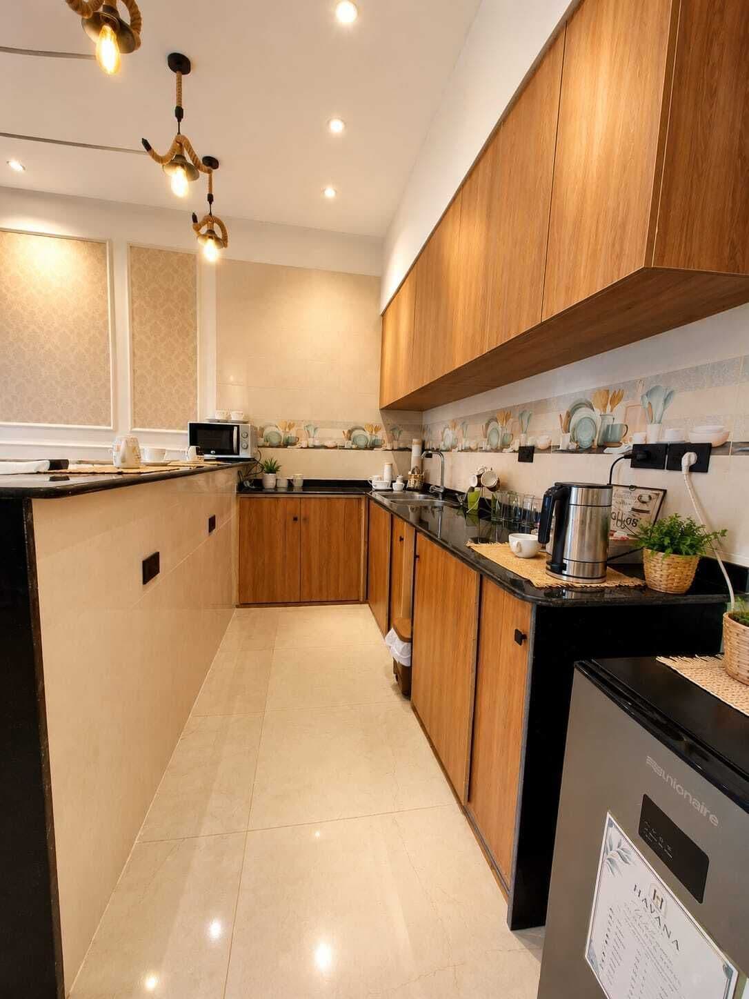 Una cocina moderna con armarios de madera, encimera negra y electrodomésticos de acero inoxidable.
