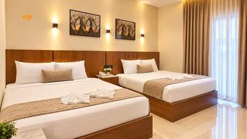 A hotel room with two beds, a wooden headboard, a bedside table with a phone, and artwork on the wall.