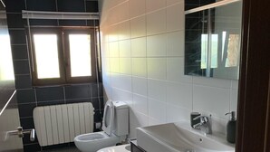Moderni kylpyhuone, jossa on valkoinen pesuallas, peili ja wc-istuin.