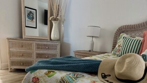 A bedroom with a bed, a nightstand, a dresser, a mirror, and a vase with dried reeds. - Modern Getaway w/ Roku TVs in Every Room Near Beach + Downtown (St. Petersburg)