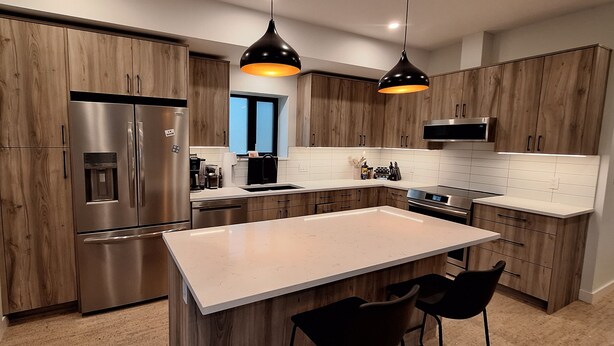 A modern kitchen with wooden cabinets, stainless steel appliances, and pendant lighting. - The Orange Bridge Lookout | Modern 2BR | Walk to Everything (Nelson)