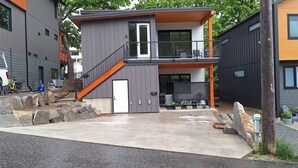 A modern two-story house with a balcony, a driveway, and a parked truck. - The Orange Bridge Lookout | Modern 2BR | Walk to Everything (Nelson)