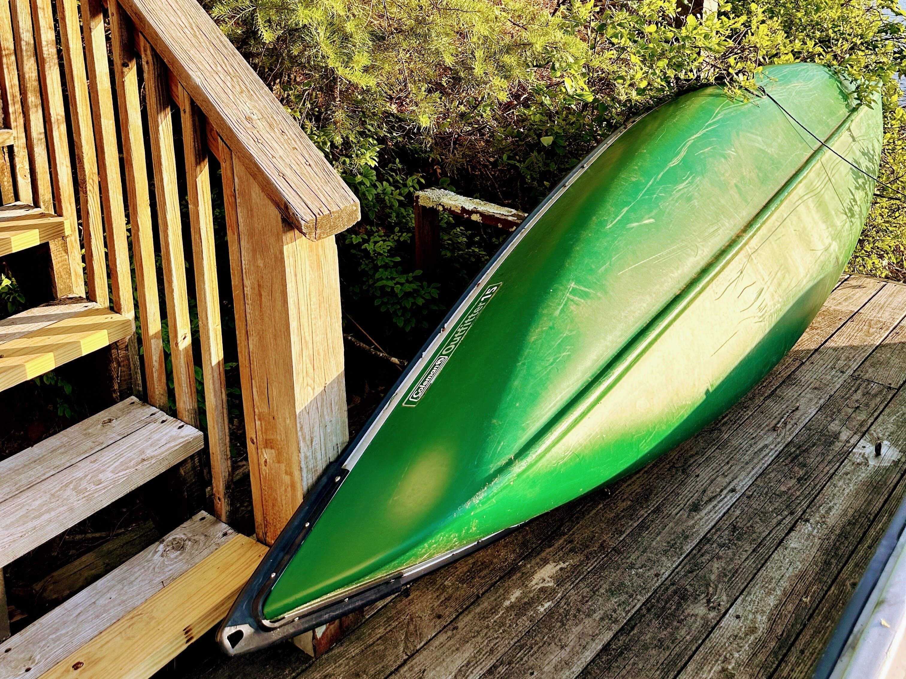 A green kayak on a wooden deck.