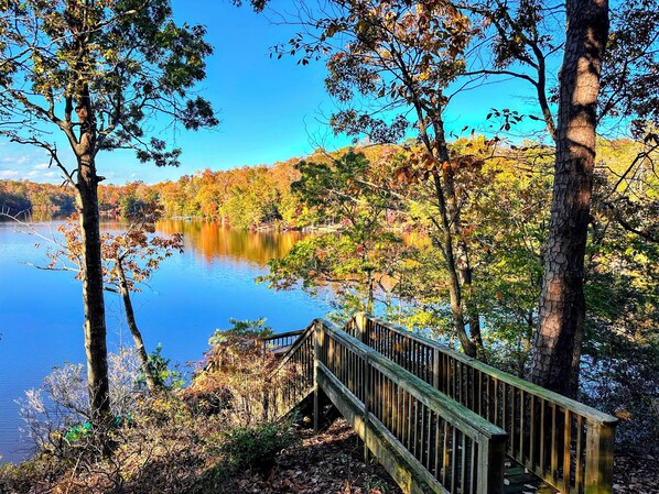 A wooden bridge leading to a lake surrounded by trees with autumn foliage. - Lakefront A-Frame: Private Dock, Kayaks & Sauna – Sleeps 12, Chesapeake Bay (Lusby)