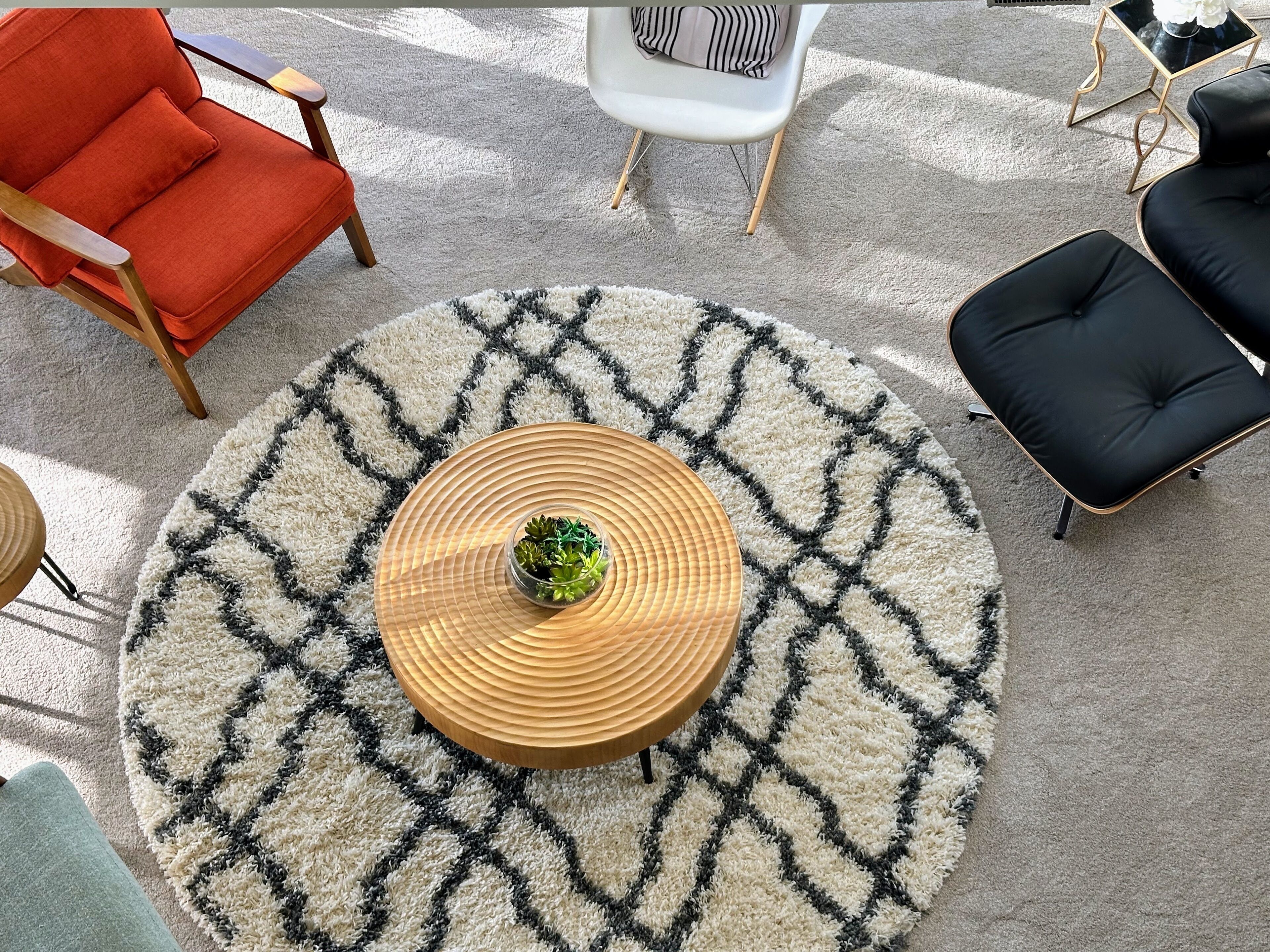 Una mesa redonda de madera con una planta en el centro, rodeada por un tapete estampado.