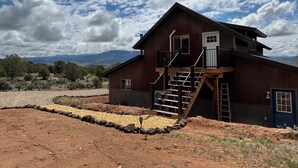 Una casa de madera rústica con un balcón y una escalera que conduce a la entrada principal.