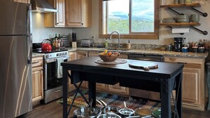 Una cocina moderna con armarios de madera, electrodomésticos de acero inoxidable y un amplio ventanal con vistas al exterior.
