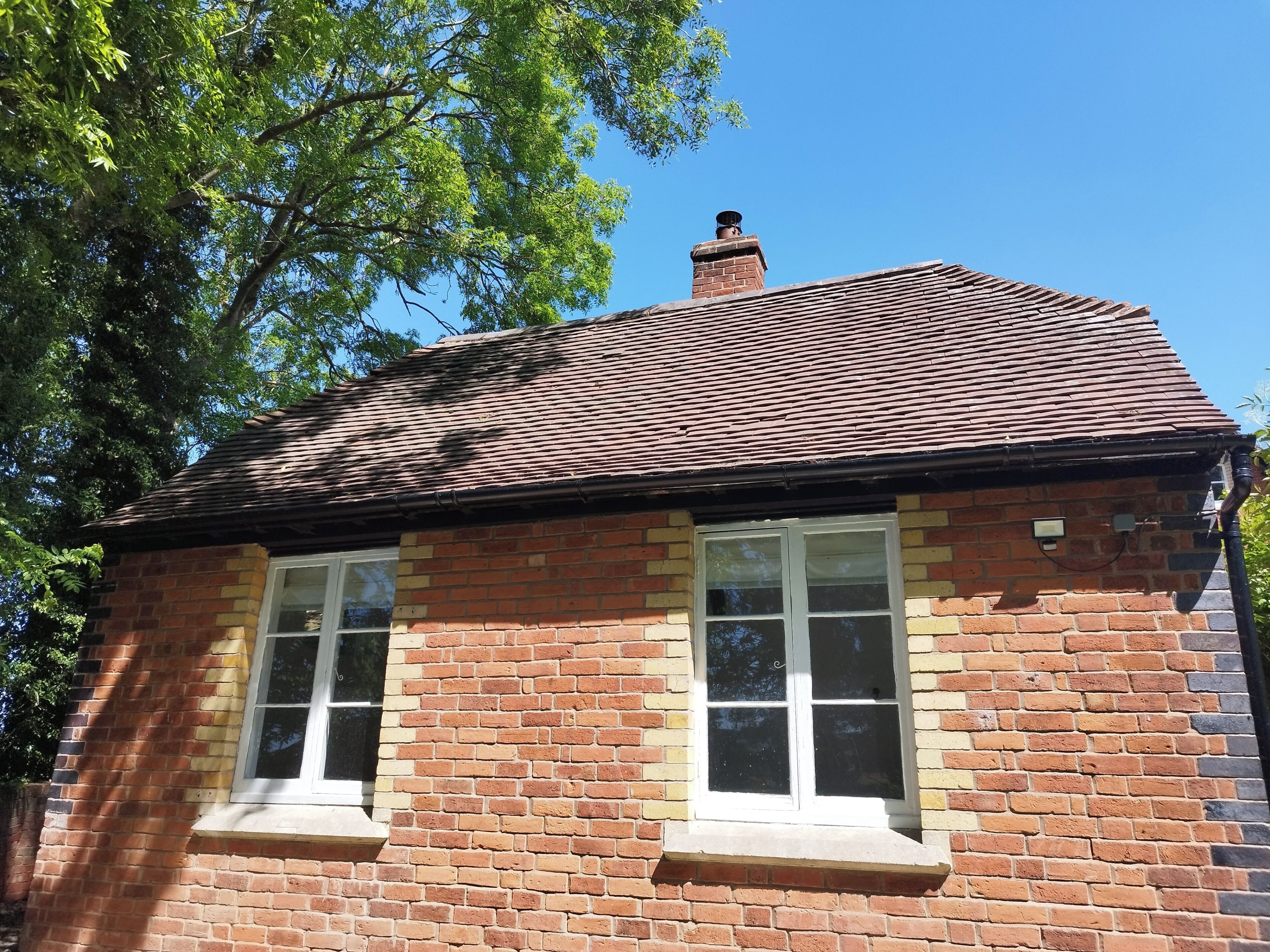 A two-story brick building with a pitched roof and two windows.