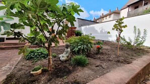 A garden with a Buddha statue, fig tree, and various plants. - Charming old town apartment within 3 minutes walking distance to the city center (Worms)