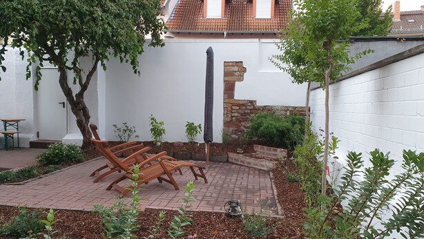 A patio with wooden chairs, a small table, and a brick pathway. - Charming old town apartment within 3 minutes walking distance to the city center (Worms)